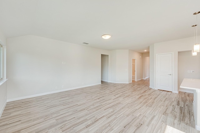 empty room with light wood finished floors, visible vents, and baseboards