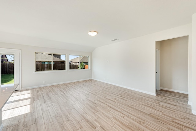 empty room featuring light wood-style floors, visible vents, plenty of natural light, and baseboards