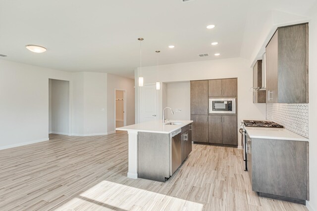 kitchen featuring decorative backsplash, a center island with sink, appliances with stainless steel finishes, and light hardwood / wood-style floors