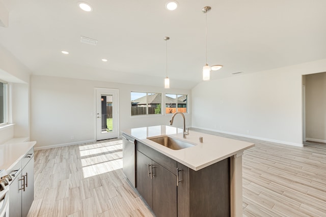 kitchen featuring light hardwood / wood-style flooring, hanging light fixtures, sink, a center island with sink, and dark brown cabinets