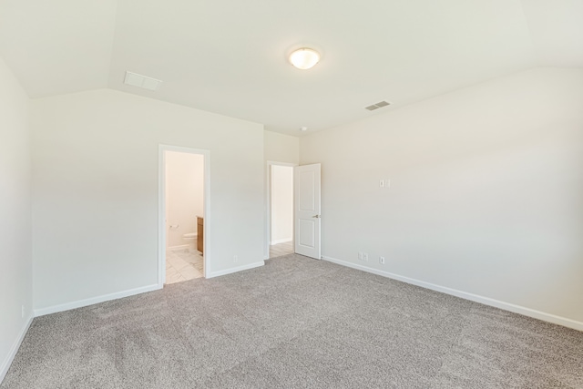 spare room featuring vaulted ceiling and light colored carpet