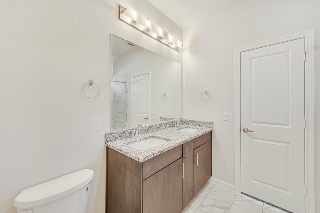 bathroom featuring toilet, marble finish floor, double vanity, and a sink