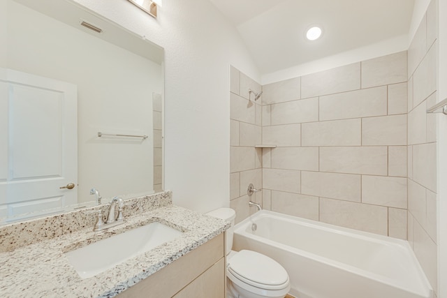 full bathroom featuring vaulted ceiling, tiled shower / bath, vanity, and toilet