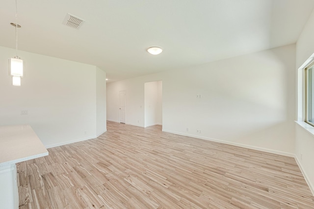 unfurnished room featuring visible vents, light wood-style flooring, and baseboards