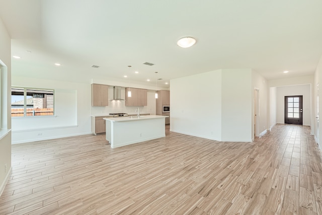 unfurnished living room featuring sink, plenty of natural light, and light hardwood / wood-style flooring