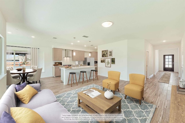 living area featuring light wood-type flooring, baseboards, visible vents, and recessed lighting