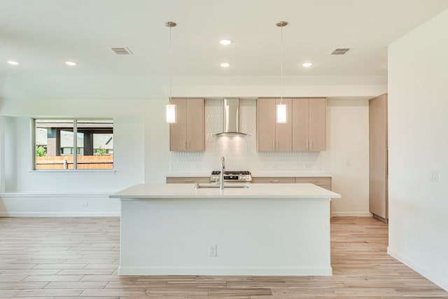 kitchen featuring pendant lighting, decorative backsplash, wall chimney range hood, and light brown cabinetry