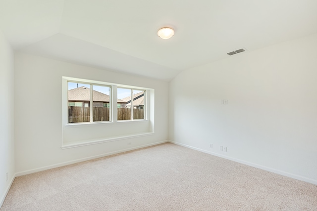 unfurnished room with light colored carpet and lofted ceiling