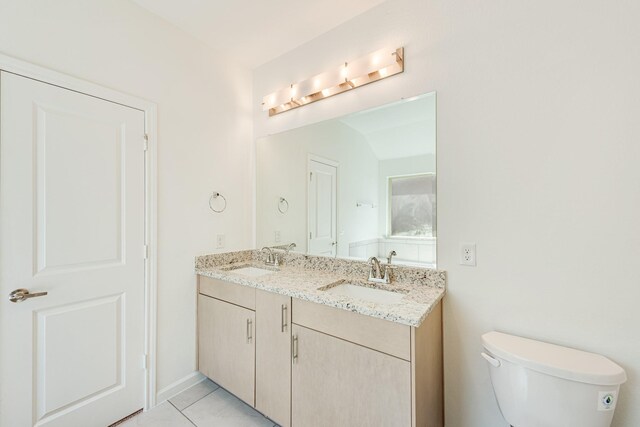 bathroom featuring toilet, double sink vanity, and tile patterned flooring