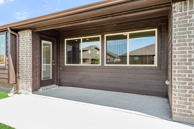 property entrance featuring a patio area and brick siding