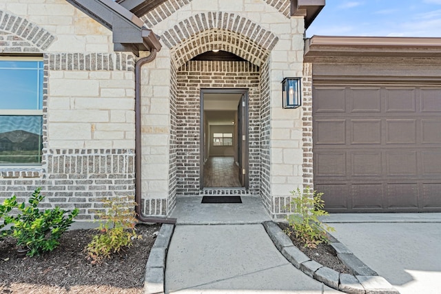 entrance to property with stone siding, brick siding, and an attached garage