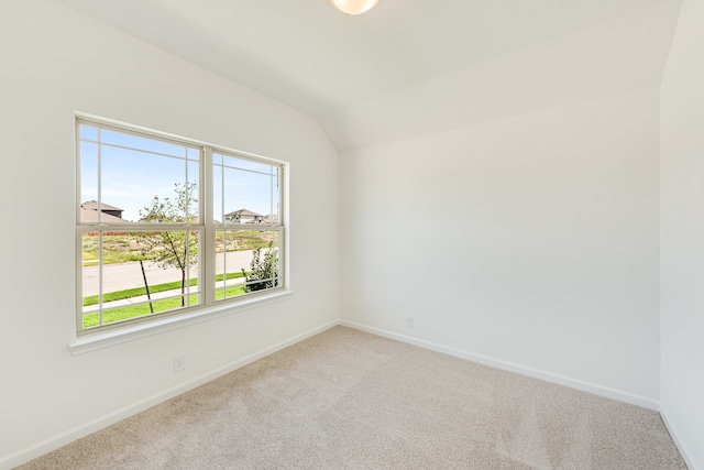 carpeted spare room with vaulted ceiling