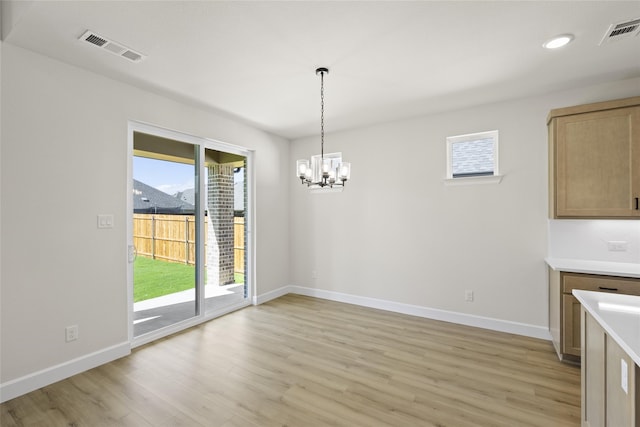 unfurnished dining area with light hardwood / wood-style flooring and a chandelier