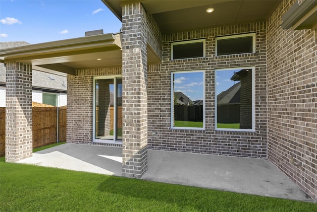 entrance to property featuring a patio area and a lawn