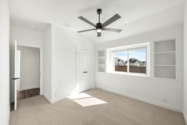 unfurnished bedroom featuring light colored carpet, vaulted ceiling, and ceiling fan