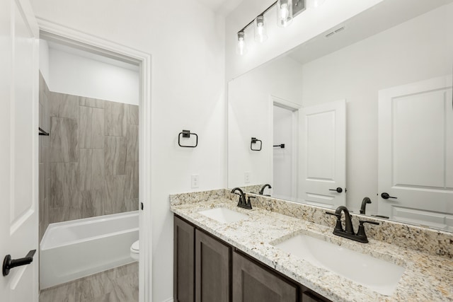 full bathroom featuring vanity, tiled shower / bath combo, and toilet