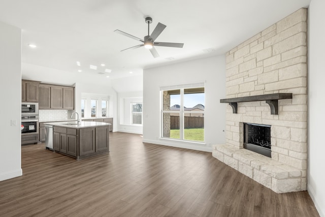 kitchen featuring dark hardwood / wood-style flooring, backsplash, stainless steel appliances, a kitchen island with sink, and sink