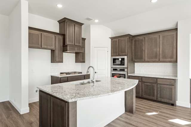 kitchen with backsplash, sink, appliances with stainless steel finishes, and an island with sink