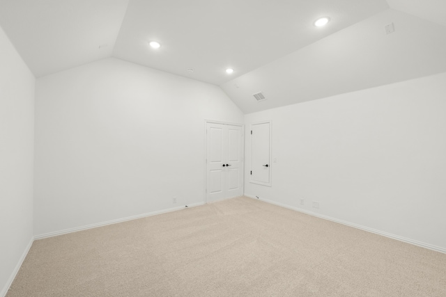 unfurnished room with light colored carpet and vaulted ceiling