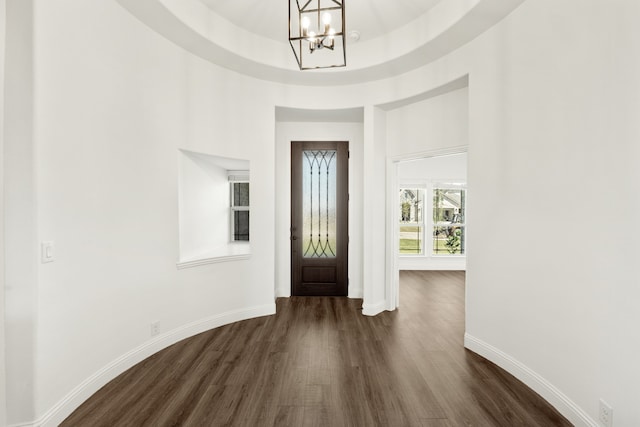 entryway featuring a raised ceiling, a chandelier, and dark hardwood / wood-style floors