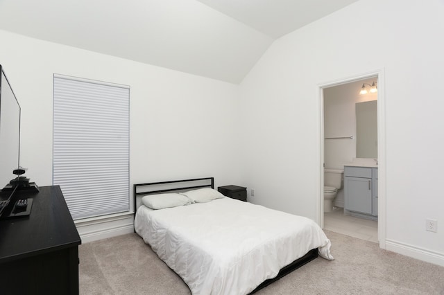 bedroom with light carpet, vaulted ceiling, and connected bathroom