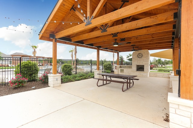 view of patio with ceiling fan, a gazebo, and an outdoor stone fireplace