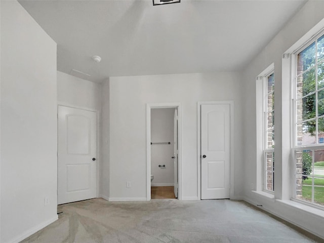 unfurnished bedroom featuring light carpet and ensuite bath