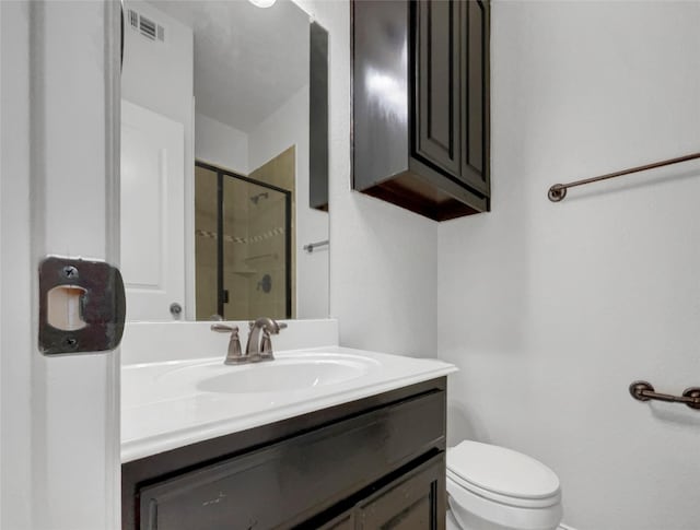 bathroom featuring vanity, toilet, and a shower with shower door