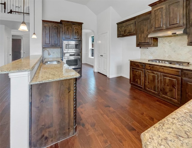 kitchen featuring appliances with stainless steel finishes, vaulted ceiling, sink, dark hardwood / wood-style floors, and hanging light fixtures