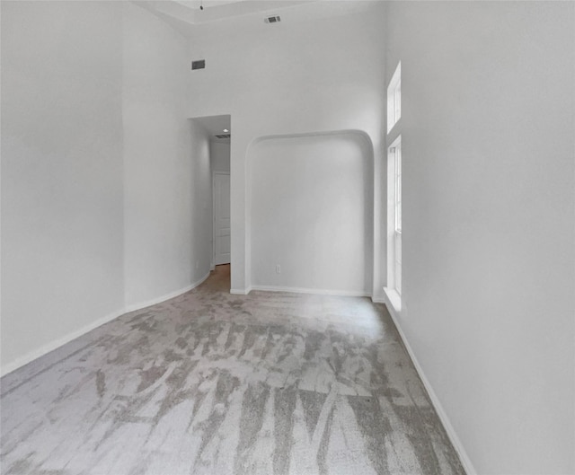 empty room featuring light colored carpet and a high ceiling