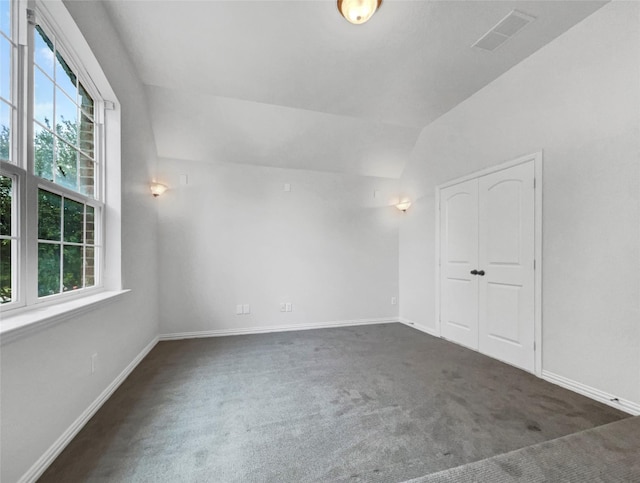 unfurnished room featuring dark colored carpet and vaulted ceiling