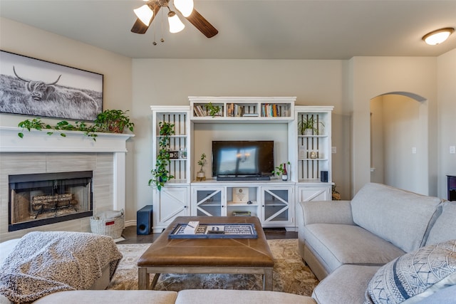 living room featuring ceiling fan, a tiled fireplace, and hardwood / wood-style flooring