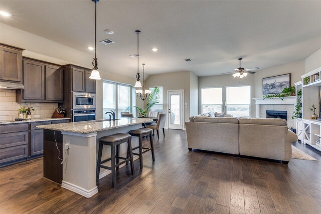 kitchen with a breakfast bar area, stainless steel appliances, backsplash, and dark wood-type flooring