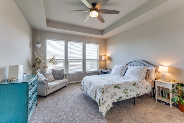 bedroom with a raised ceiling, ceiling fan, and carpet flooring