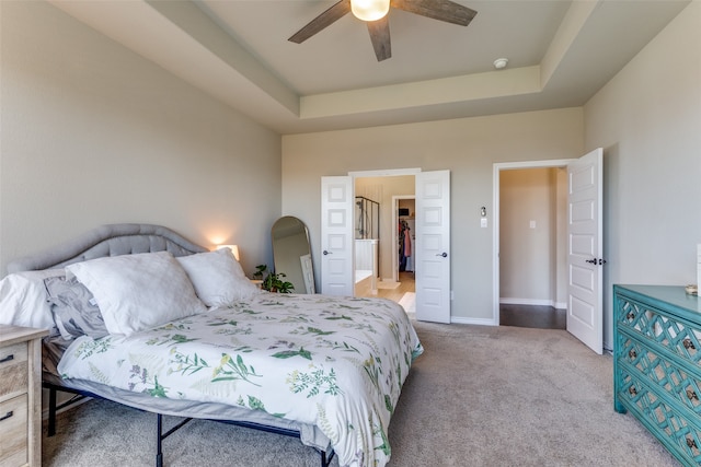 carpeted bedroom with ceiling fan and a tray ceiling