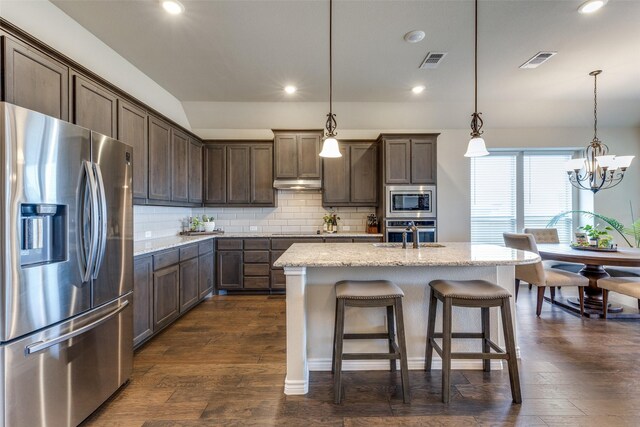 kitchen featuring dark hardwood / wood-style floors, stainless steel appliances, tasteful backsplash, and hanging light fixtures