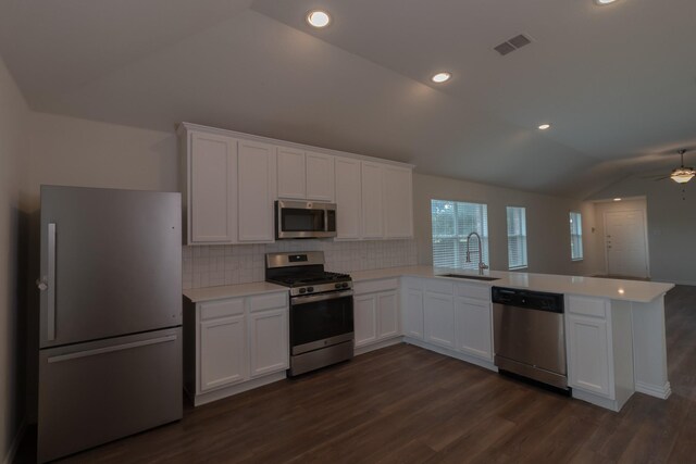 kitchen featuring sink, vaulted ceiling, kitchen peninsula, white cabinetry, and appliances with stainless steel finishes