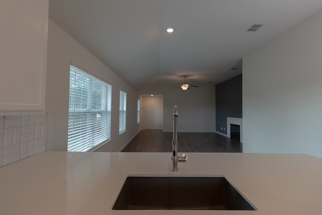 kitchen with decorative backsplash, dark wood-type flooring, lofted ceiling, ceiling fan, and sink