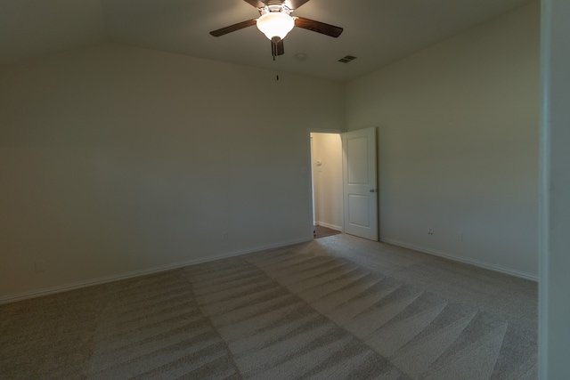 carpeted spare room featuring vaulted ceiling and ceiling fan