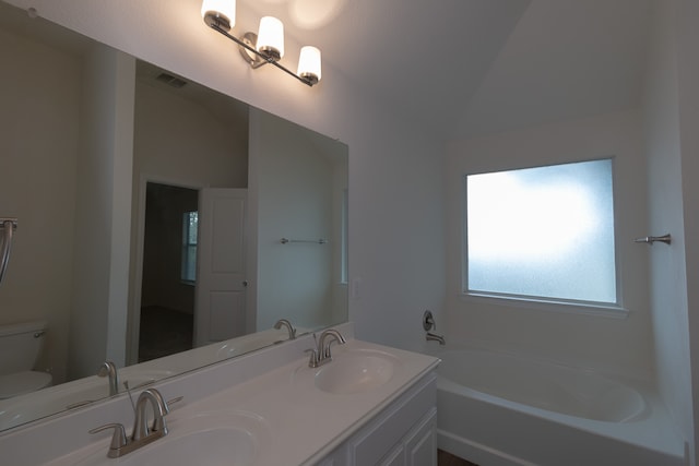 bathroom with vanity, vaulted ceiling, a bathtub, and toilet