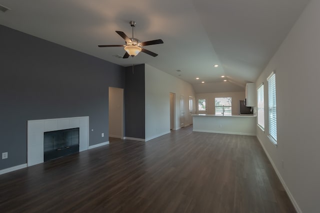 unfurnished living room featuring a tiled fireplace, ceiling fan, vaulted ceiling, and dark hardwood / wood-style flooring