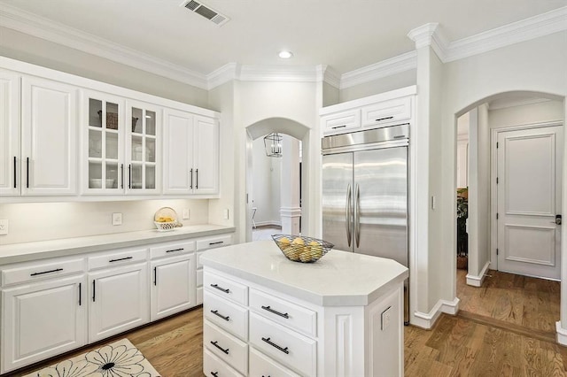 kitchen featuring a center island, white cabinets, stainless steel built in fridge, crown molding, and light wood-type flooring