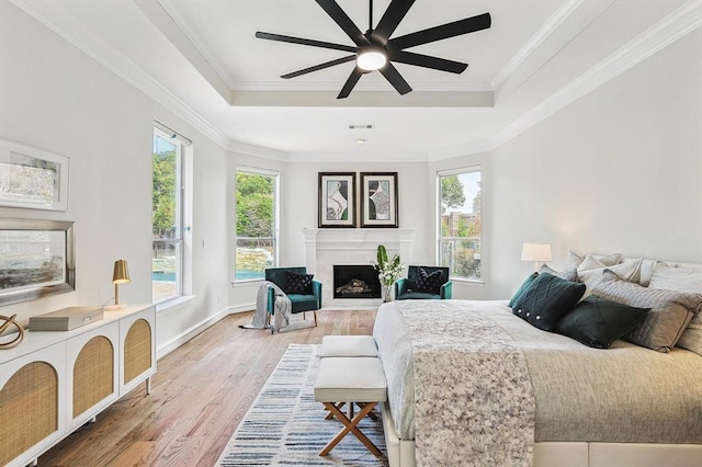 bedroom with hardwood / wood-style floors, ceiling fan, a raised ceiling, and ornamental molding