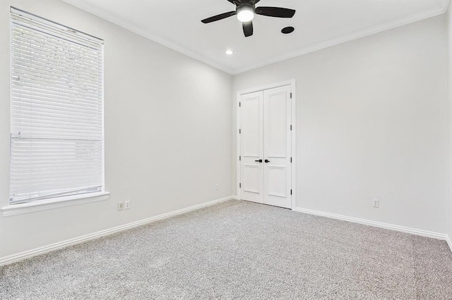 carpeted spare room with ceiling fan and crown molding