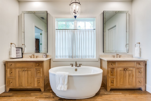 bathroom featuring dual vanity, a bathing tub, and hardwood / wood-style floors