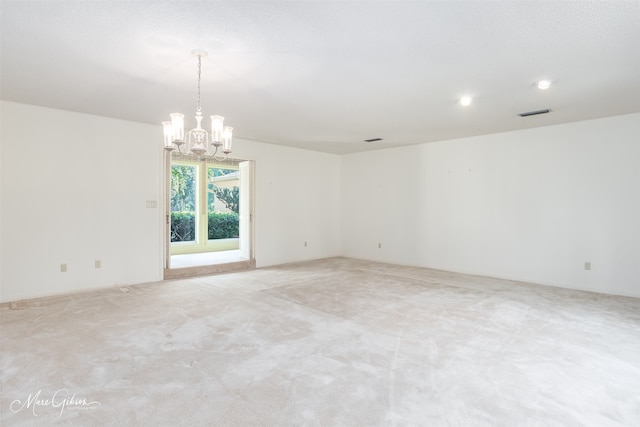 carpeted spare room featuring a notable chandelier