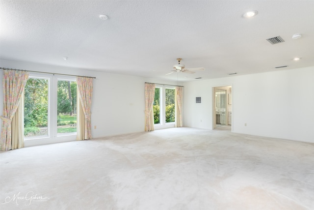 carpeted spare room with ceiling fan and a textured ceiling