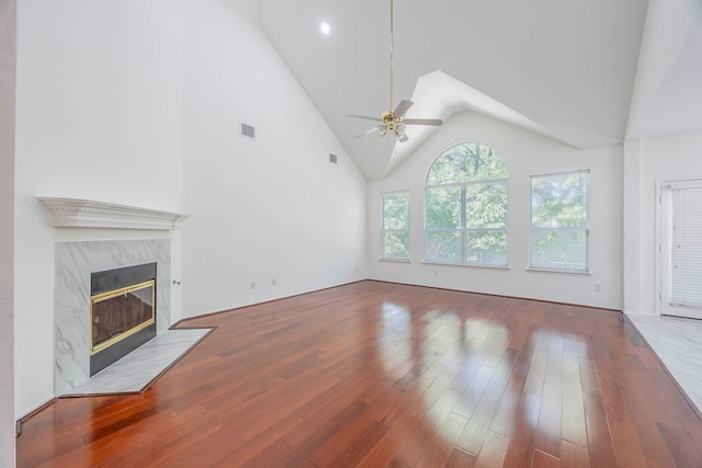 unfurnished living room featuring high vaulted ceiling, ceiling fan, a fireplace, and hardwood / wood-style floors