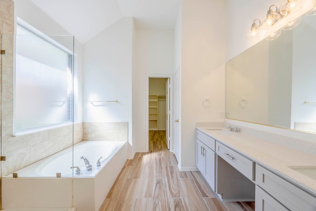 bathroom featuring wood-type flooring, lofted ceiling, vanity, and plus walk in shower