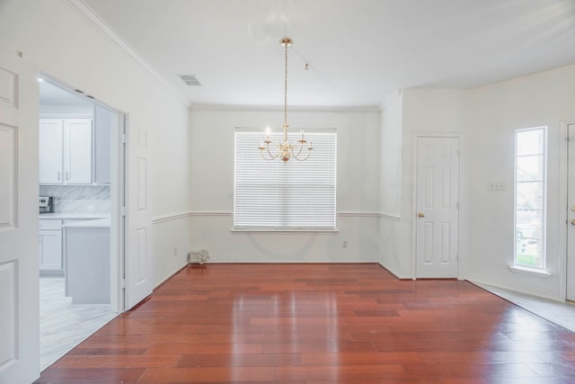 unfurnished dining area with crown molding, dark hardwood / wood-style flooring, and a chandelier